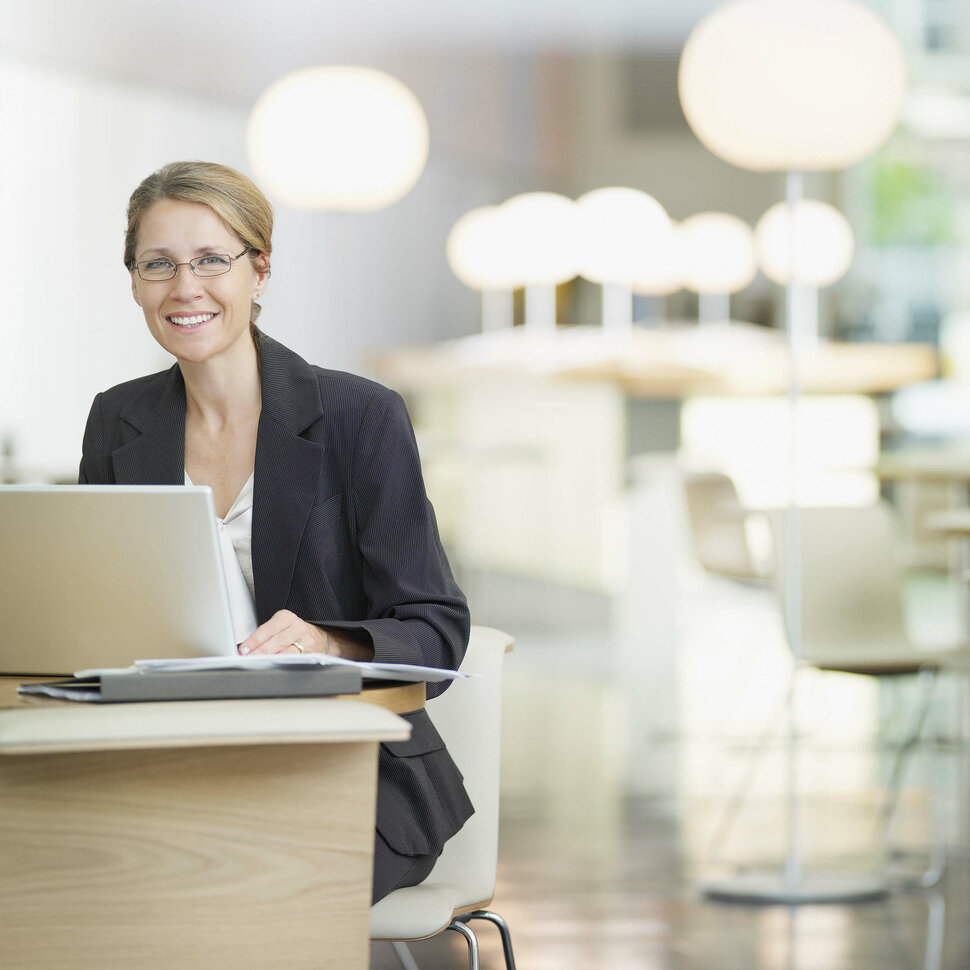 Eine Frau sitzt am Laptop in einer hellen Bürolobby