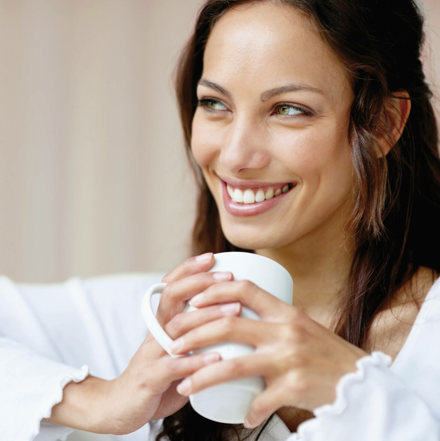 Eine Frau hält eine Kaffeetasse und lächelt